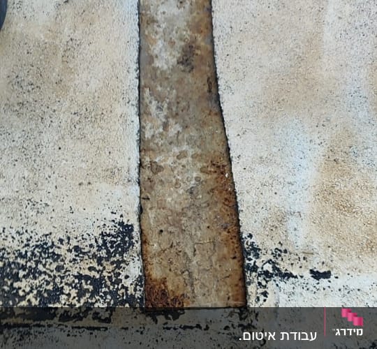 חלק מתכת חלוד מוקף בחומר איטום שחור